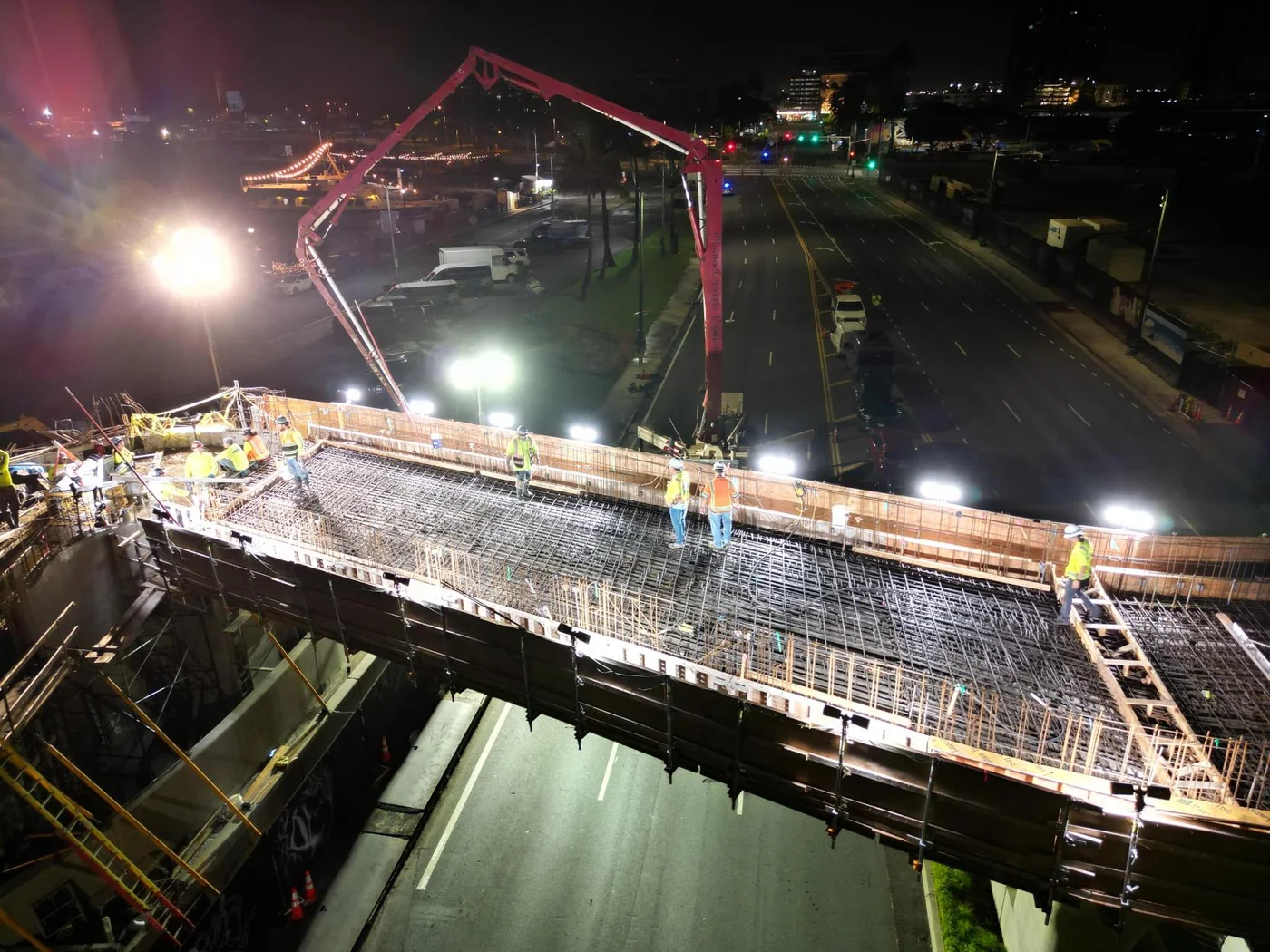 Nighttime concrete placement on the elevated pedestrian walkway deck.