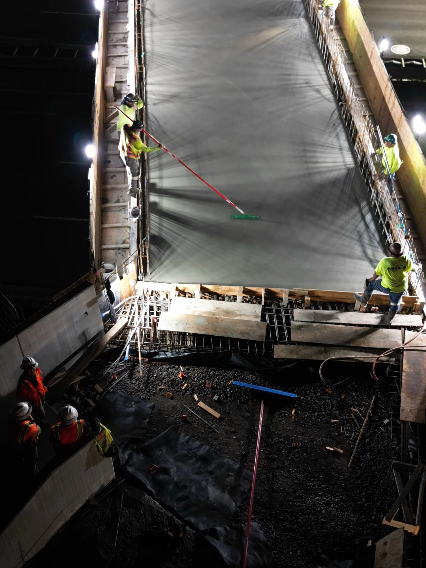 Crew coordinating a concrete pour on the pedestrian walkway structure.