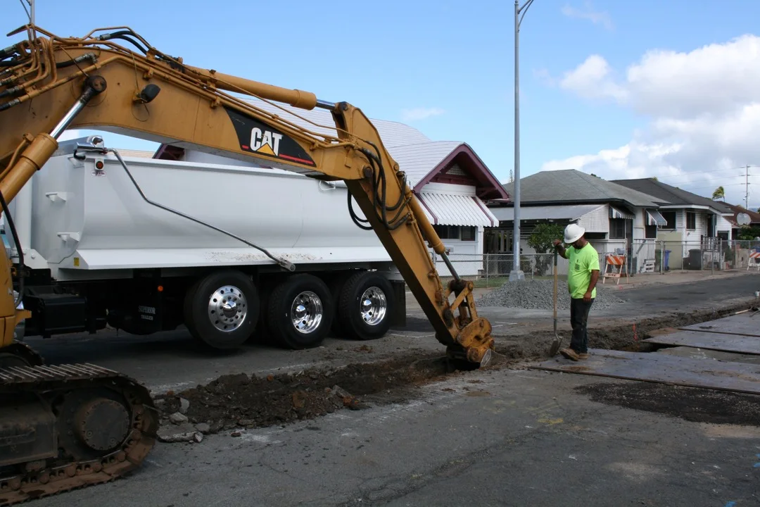 Excavation equipment and crew advancing waterline work along the street.