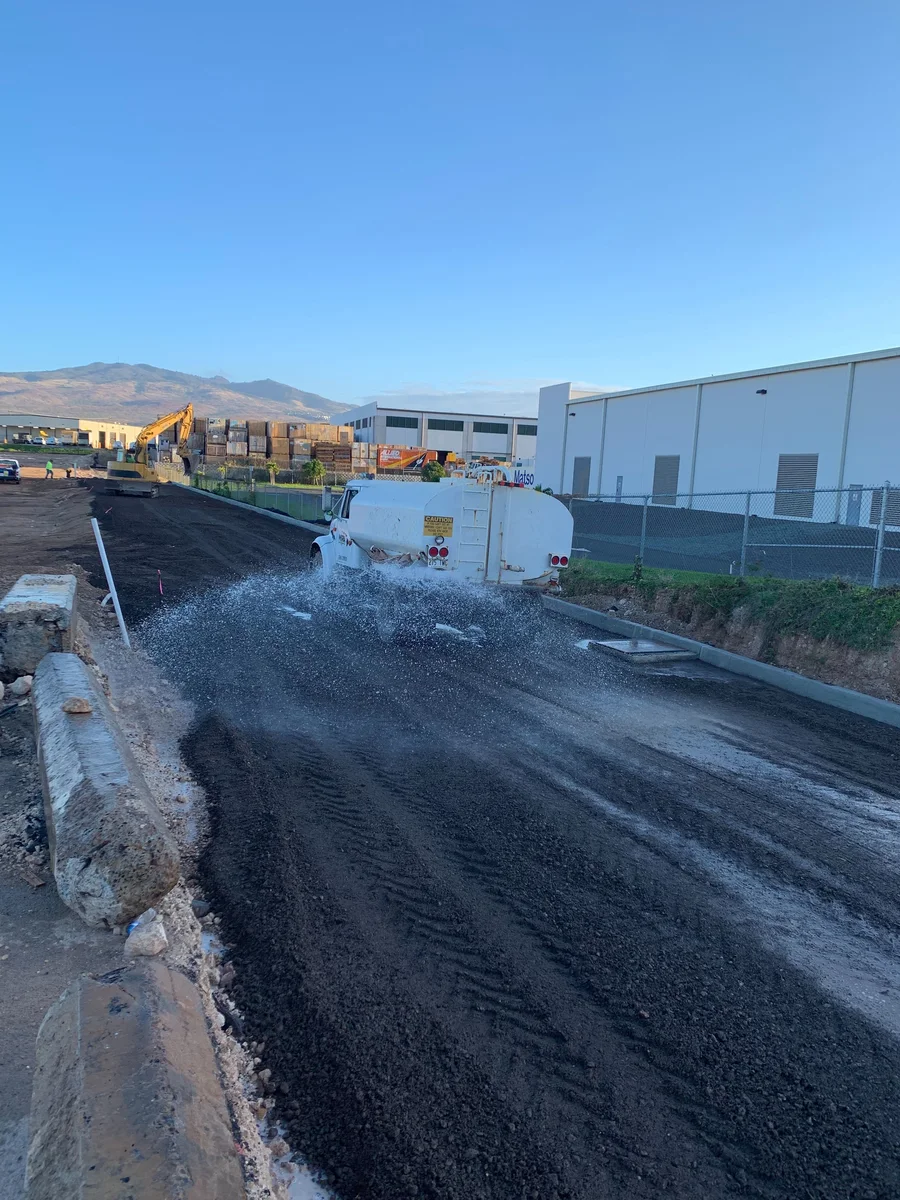 Watering and compaction work during industrial-site construction.