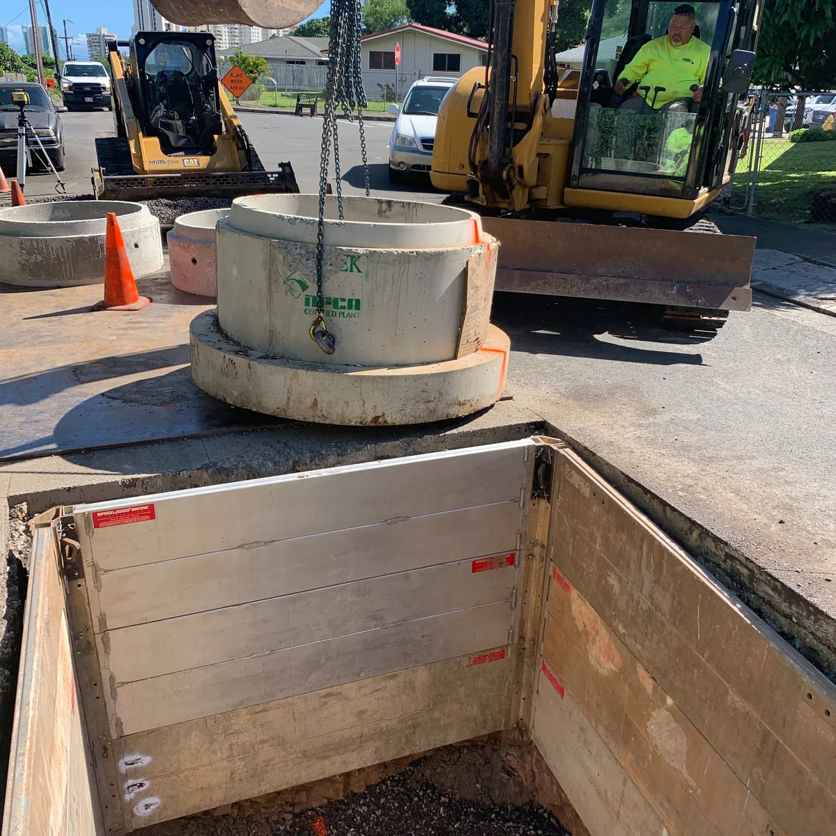 Excavator work supporting sewer improvements on a constrained site.