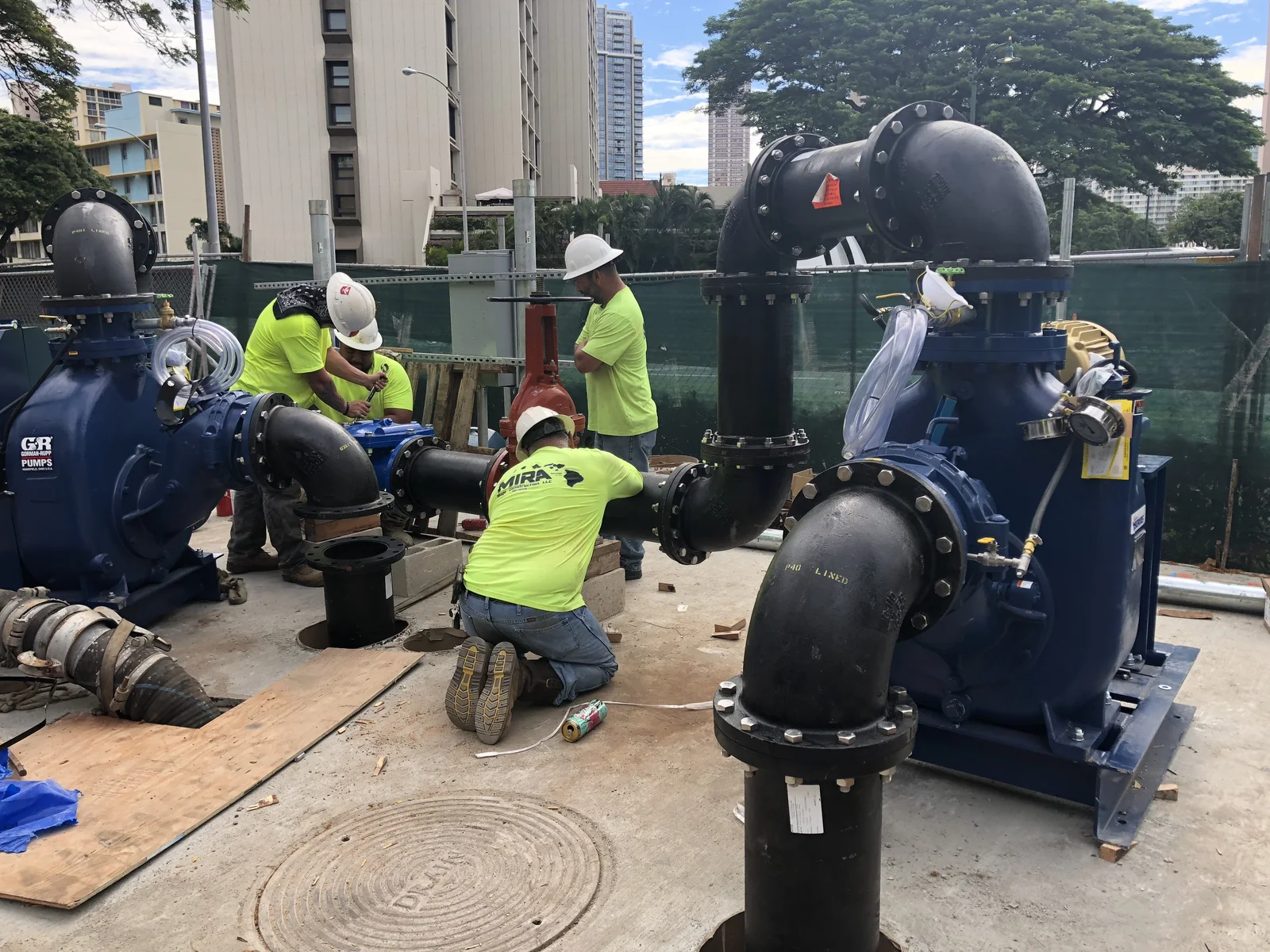 MIRA crew breaking pavement over a manhole inside the Ala Moana Center parking structure at night.